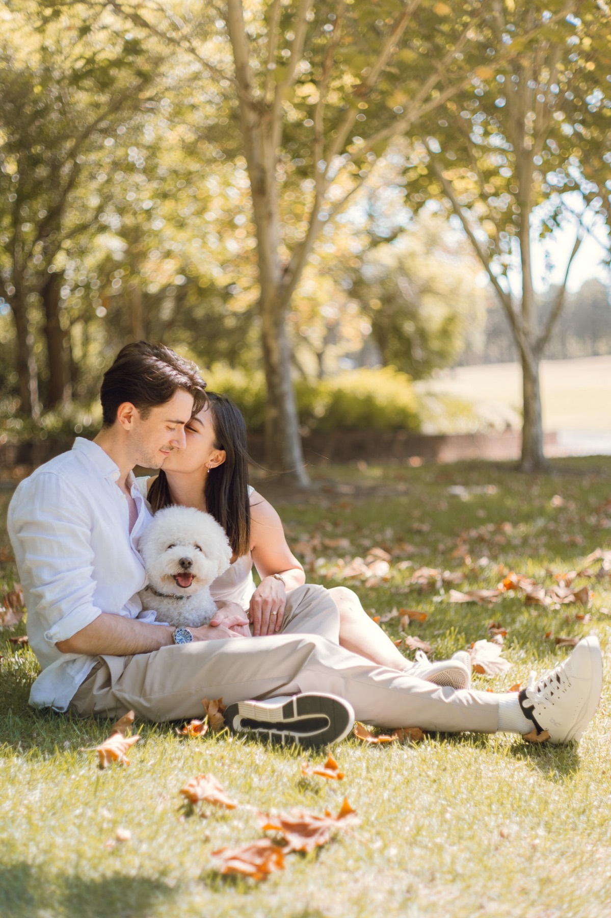 The couple kissing on the grass under the trees with Marlo in Damon's lap