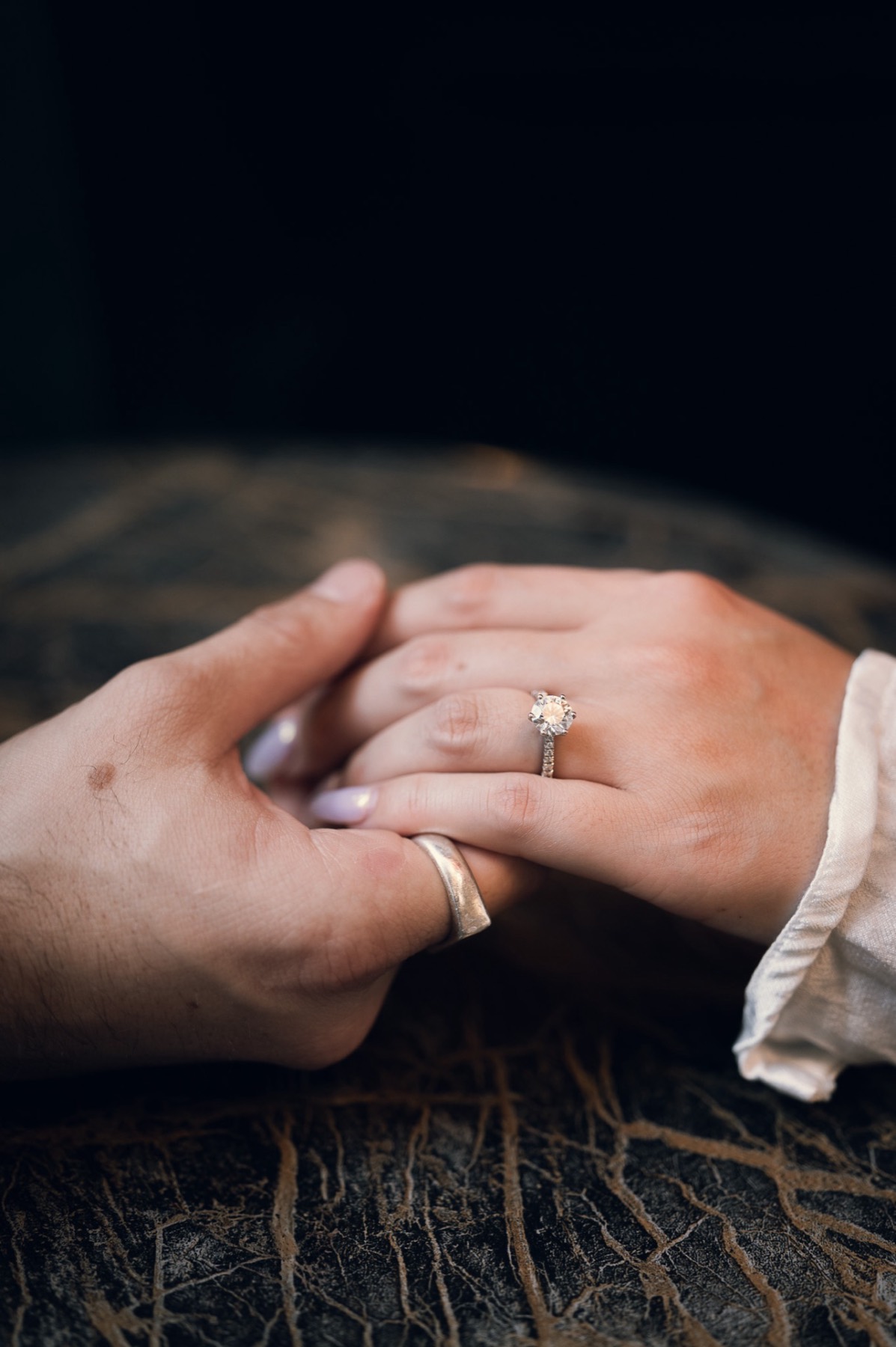 Close-up of the couple's hands, Kim's engagement ring and Dave's band catching the light
