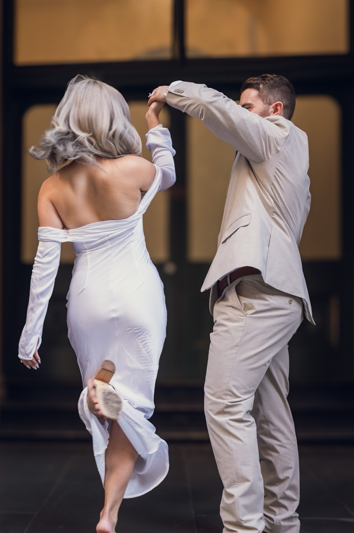 Dave twirling Kim in front of tall windows, her dress swinging